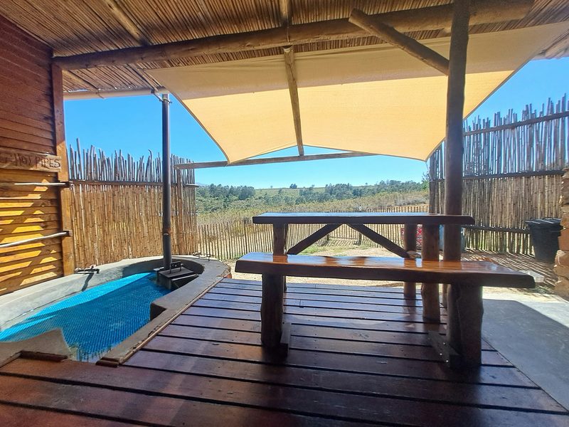 BushCat patio with a shade sail, a log table and the hot tub