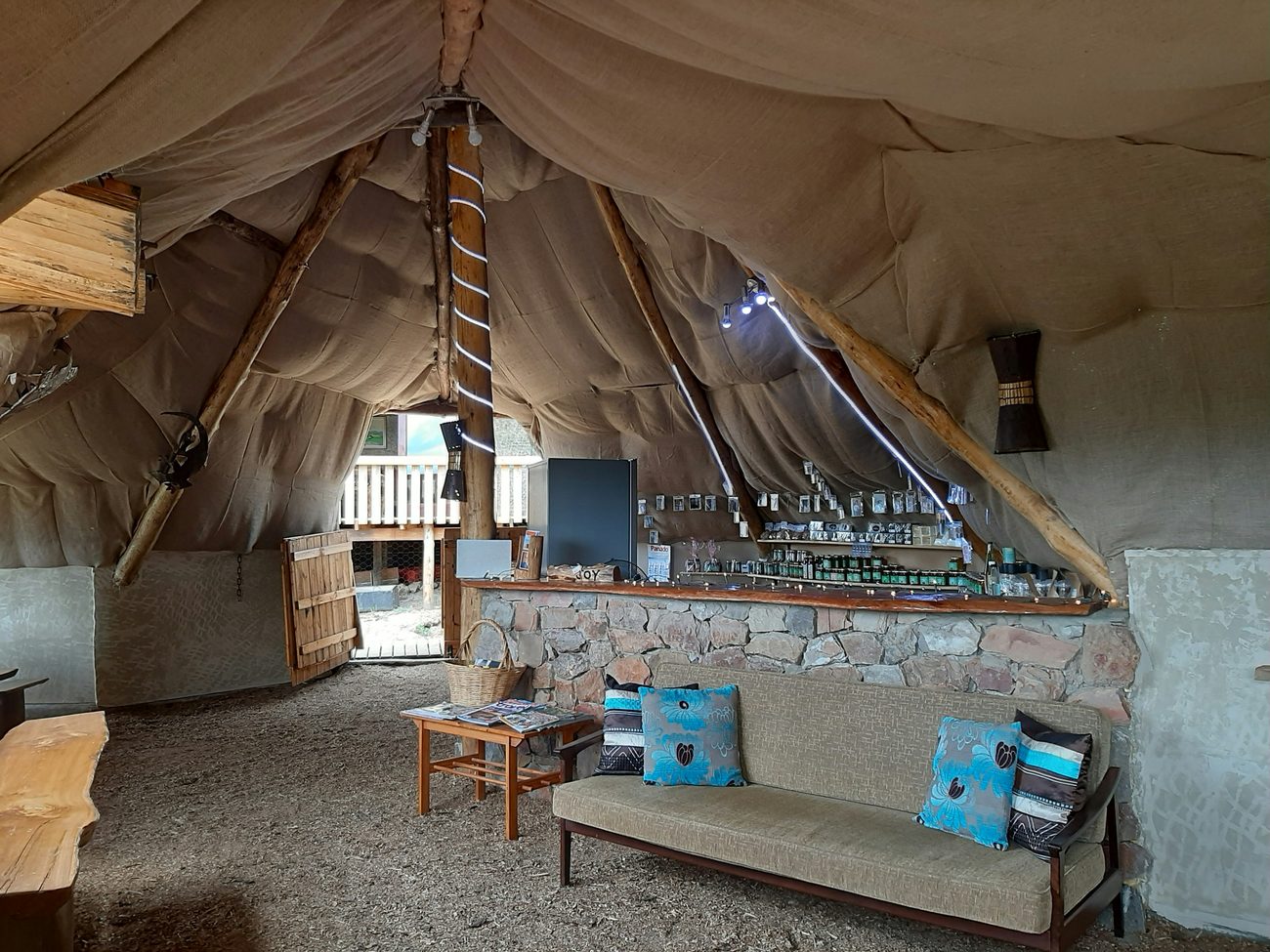 Inside the thatched lapa: a stone counter lined with jars and a couch with blue cushions