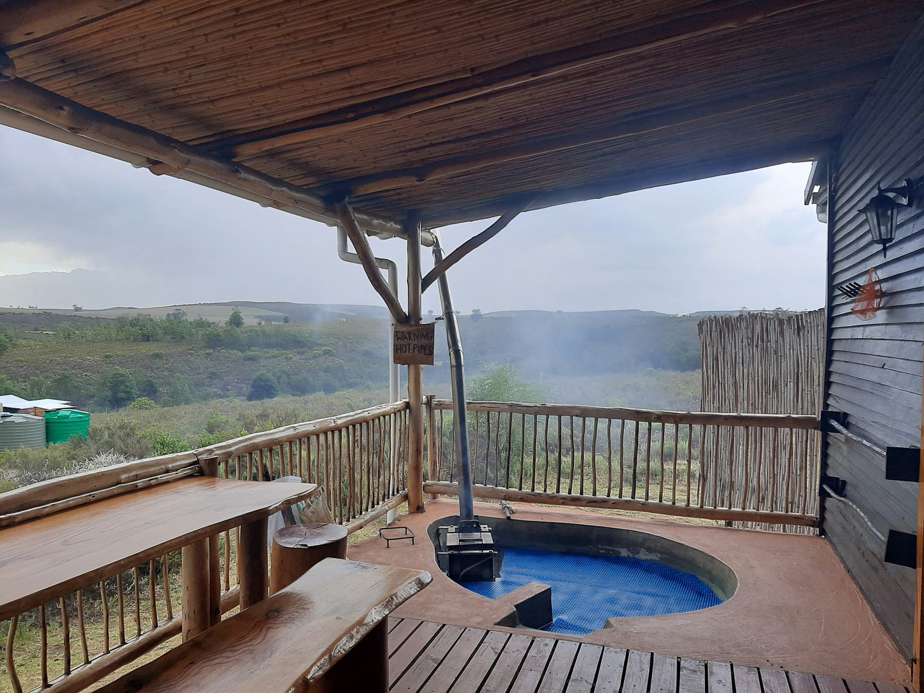 Vlakvark's covered patio on a grey morning, its wood-fired hot tub steaming beside the chimney